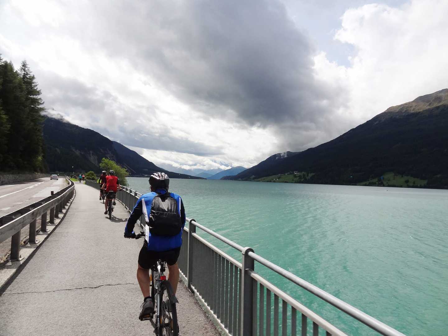 Radreise Deutschland Österreich Italien Via Claudia Augusta, Launer-Radgruppe von hinten einen Fahrradweg entlang des Reschensees befahrend