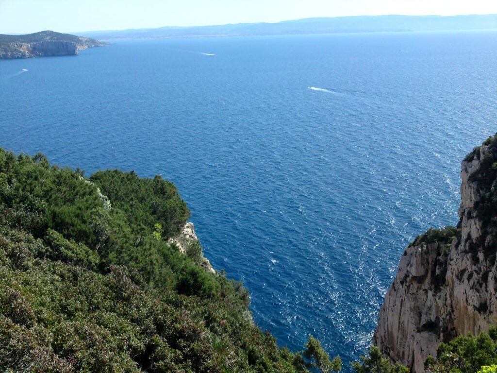 Rennradreise Italien Sardinien, Blick eine felsige Schlucht hinunter auf das dunkelblaue Mittelmeer