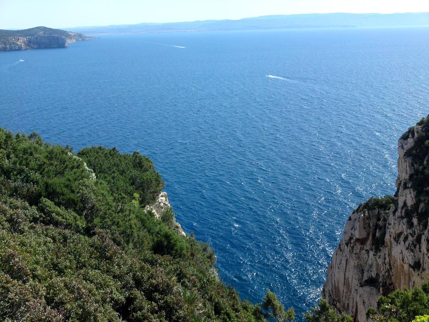 Rennradreise Italien Sardinien, Blick eine felsige Schlucht hinunter auf das dunkelblaue Mittelmeer