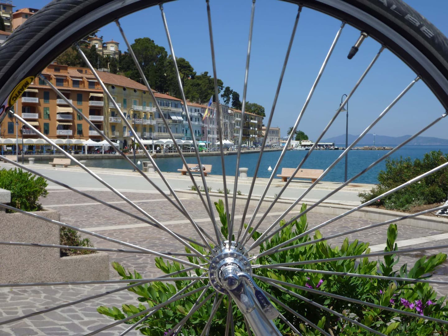 Radreise Italien Alpen-Rom, Strandpromenade am Mittelmeer durch ein Laufrad fotografiert