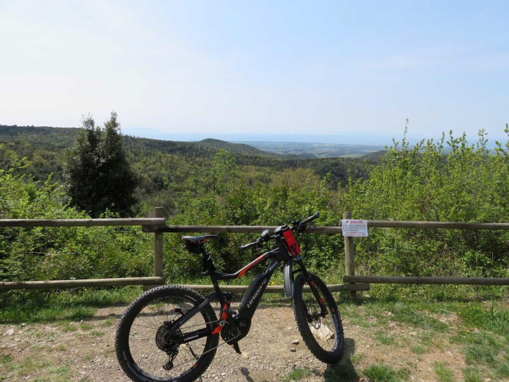 Radreise Italien Toskana Küste, abgestelltes E-Bike an einem Aussichtspunkt mit Blick über die toskanische Landschaft