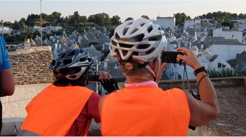 Italien Apulien - Radfahrer vor Trulli Häuser in Alberobello